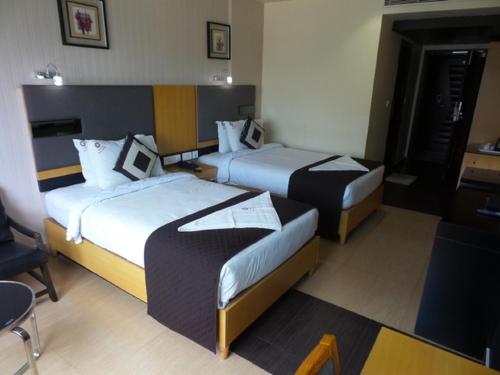a hotel room with two beds and a table at Mayas Kem Pride A Group of hotel Mayas in Tiruchchirāppalli