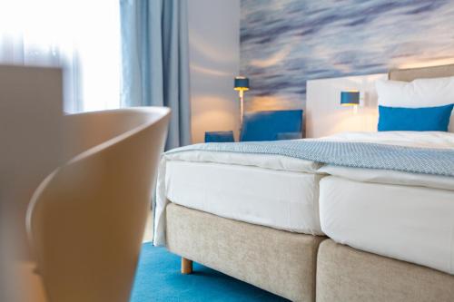 a hotel room with a bed and a painting on the wall at Stratmanns Haus am See in Lembruch