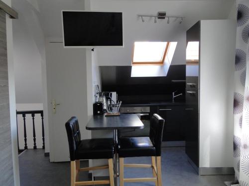 une petite cuisine avec une table et des chaises noires dans l'établissement Tout confort et proximité., à Vichy