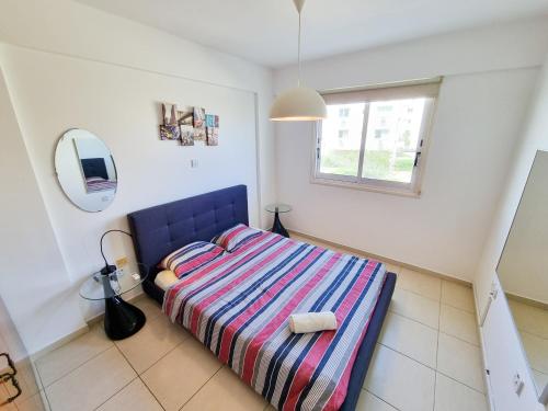 a bedroom with a bed with a striped blanket and a mirror at Seaside Heaven Apartment With Pool in Larnaca