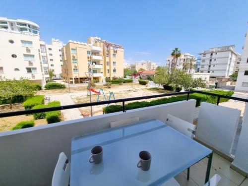 a white table on a balcony with a view of buildings at Seaside Heaven Apartment With Pool in Larnaca