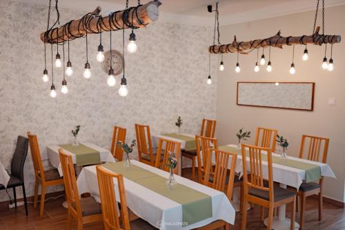 a dining room with tables and chairs and lights at City Inn Szigetvar in Szigetvár