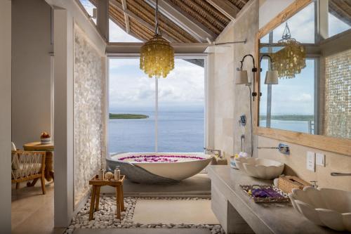 a bathroom with a tub with a view of the ocean at Pramana Natura Nusa Penida in Nusa Penida