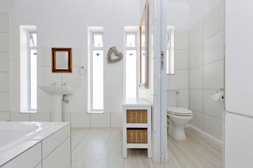 a white bathroom with a toilet and a sink at Kite Beach House Langebaan in Langebaan