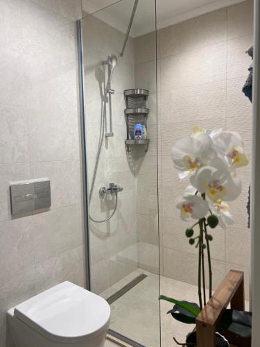 a bathroom with a shower with a toilet and flowers at Belgrade Waterfront Escape 104 in Belgrade