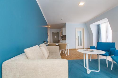 a living room with a white couch and blue chairs at Stratmanns Haus am See in Lembruch