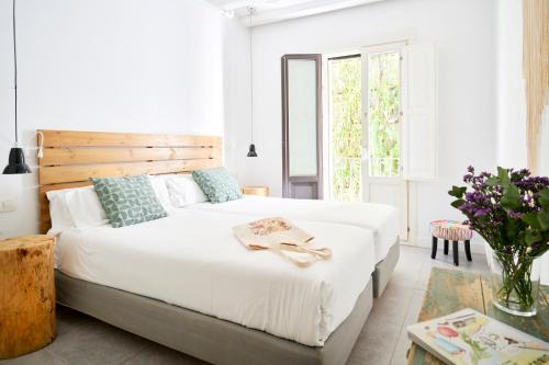 a bedroom with a large white bed with a wooden headboard at Eco Boutique Hostal Grau in Barcelona