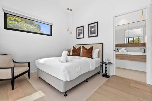 a white bedroom with a large bed and a bathroom at Beach Luxury On The Park - Brand New, Central! in Ocean Grove
