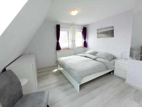 1 dormitorio blanco con 1 cama y 1 silla en Mühlenpanorama - Ferienhaus in Kappeln an der Schlei, en Kappeln