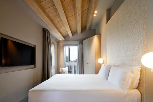 a bedroom with a white bed and a television at Hotel Dei Dragomanni in Venice