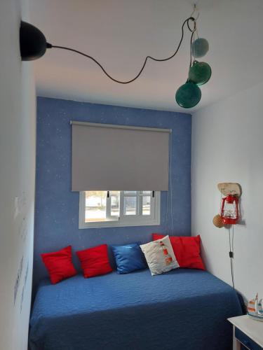 Un dormitorio con una cama azul con almohadas rojas y azules en Casa Elsa, en Puerto del Rosario