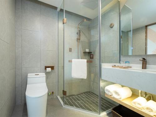 a bathroom with a shower and a toilet and a sink at Chaoman Hotel -Guangzhou Shijing City Plaza Xiaoping Subway Station in Guangzhou