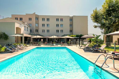 una piscina en un hotel con sillas y sombrillas en Best Western PLUS Elixir Grasse, en Grasse