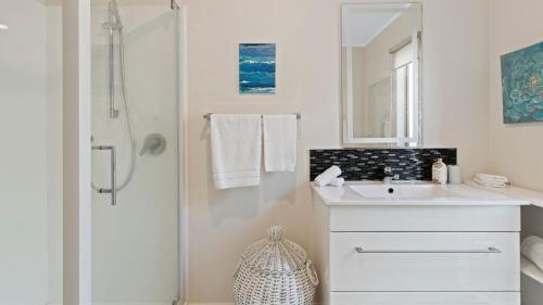 Little Manly Cottage - Manly Holiday Home في وانغاباراوا: حمام أبيض مع حوض ودش