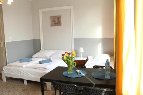 a room with a bed and a table with flowers on it at Hacienda in Sopot