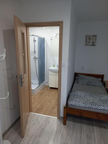 1 dormitorio con 1 cama y baño con ducha en Noclegi Stacja Wilkołaz, 