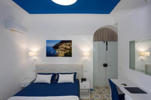 a bedroom with a blue ceiling and a bed and a sink at Locanda Costa D'Amalfi in Amalfi