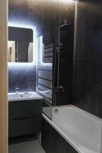 een badkamer met een bad, een wastafel en een spiegel bij NL group apartments in Kolomiya