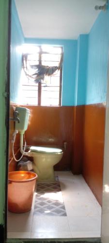 a bathroom with a toilet and a window at M B Holiday Home in Guwahati