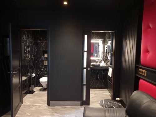 a black bathroom with a toilet and a sink at Hotel et Spa Le Lion d'Or in Pont-lʼÉvêque