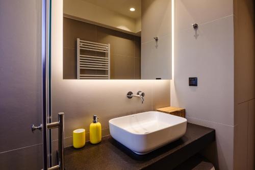 W łazience znajduje się biała umywalka i lustro. w obiekcie Goudi 4th Floor Greece Apartments w Atenach