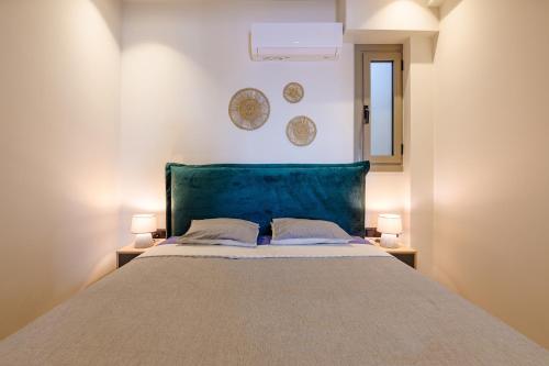 ein Schlafzimmer mit einem Bett mit zwei Lampen und zwei Platten an der Wand in der Unterkunft Goudi 4th Floor Greece Apartments in Athen