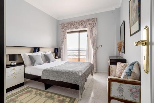 1 dormitorio con cama, ventana y silla en ALTIDO Vibrant flat with balcony, en Costa da Caparica