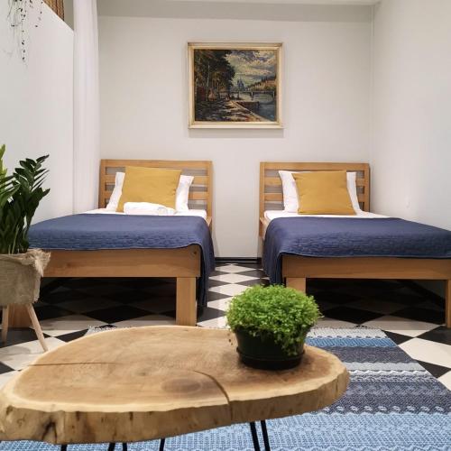 two twin beds in a room with a table and a table sidx sidx at Moonrise Apartment in Mostar