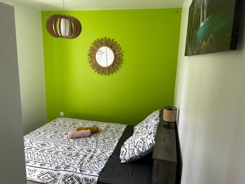 a green room with a bed with a mirror at VillaCalmflor in Sainte-Anne