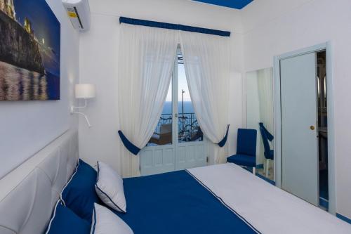 a bedroom with a blue and white bed and a window at Locanda Costa D'Amalfi in Amalfi