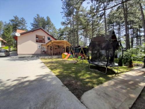 un patio trasero con un parque infantil y una casa en Apartmani Jela Tara en Kaludjerske Bare