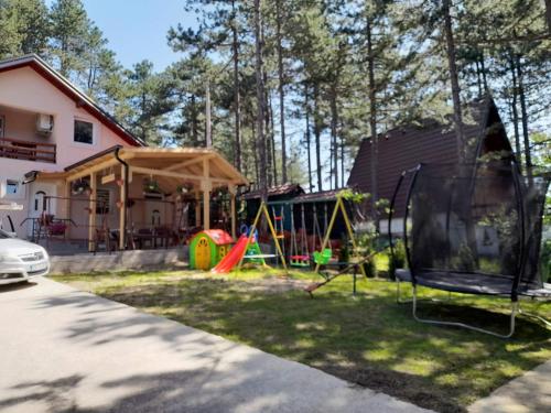 un patio con parque infantil y una casa en Apartmani Jela Tara en Kaludjerske Bare