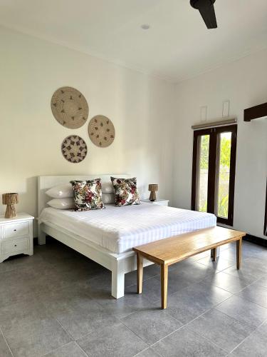 a bedroom with a white bed and a wooden bench at Asri Villas Bingin in Uluwatu