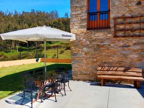 a patio with a table and a bench and an umbrella at Casa Carmelo in Viveiro