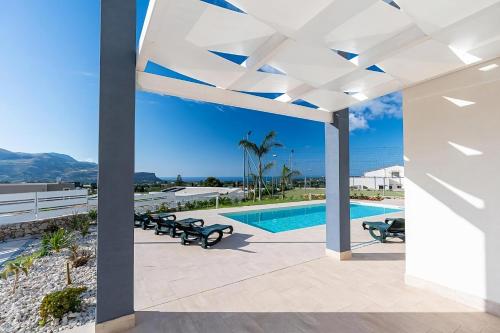 une terrasse avec une piscine et des bancs à côté d'un bâtiment dans l'établissement Villa Sikania Seaview Scopello, à Castellammare del Golfo