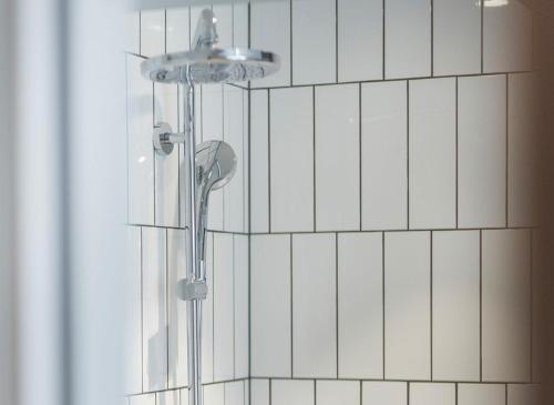 a shower in a bathroom with white tiles at UNITY Malmö in Malmö