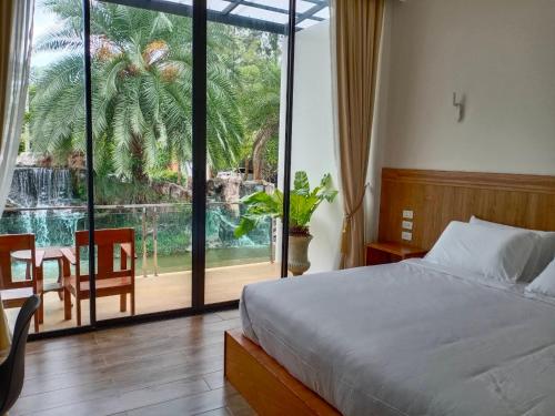 1 dormitorio con 1 cama y una gran ventana de cristal en The Grand Jamjuree Resort Lamphun 