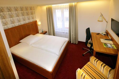 a hotel room with a bed and a desk and a computer at Bayerischer Hof in Freising