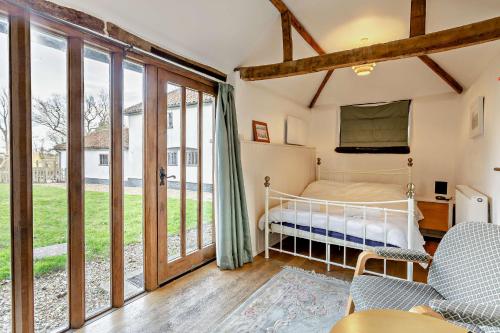 a bedroom with a bed and sliding glass doors at The Retreat in Tibenham