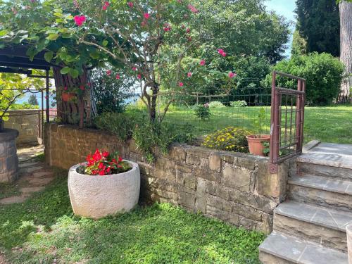 un jardín con una pared de piedra y un árbol con flores rosas en Apartments Portoroz, en Portorož