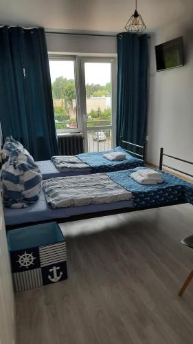 een slaapkamer met een bed en een groot raam bij Apartament 3 pokoje z balkonem Asklepios in Świnoujście