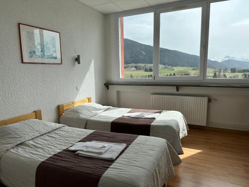 a hotel room with two beds and a large window at L'ESCANDILLE Village Vacances in Autrans