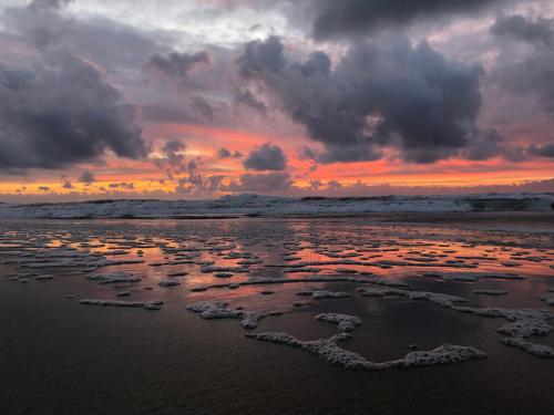 a sunset on the beach with rocks in the sand at Fresh hytte ved Borestranden med to soverom og hems in Klepp