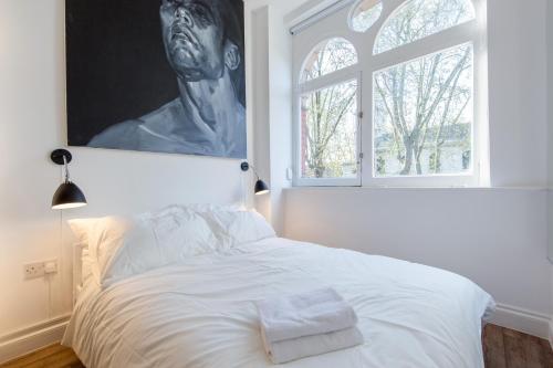 um quarto com uma cama branca e uma grande janela em St. Lukes View, Shoreditch, by the Design Traveller em Londres
