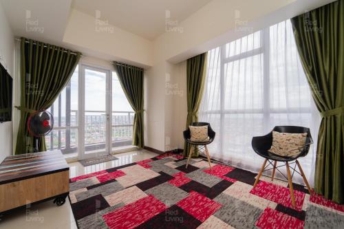 a living room with two chairs and large windows at RedLiving Apartemen Vida View - Vida Connect in Pampang