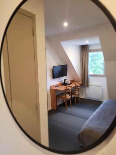 a mirror reflecting a room with a table and a desk at The Originals City, H&ocirc;tel Novella, Nantes Centre Gare in Nantes