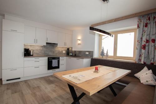 uma cozinha com armários brancos e uma mesa de madeira em Ferienwohnung Bergpanorama WILD600 em Auffach