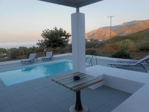 einen Pool mit 2 Stühlen und einem Tisch in der Unterkunft Grand Villa Lino in Skyros