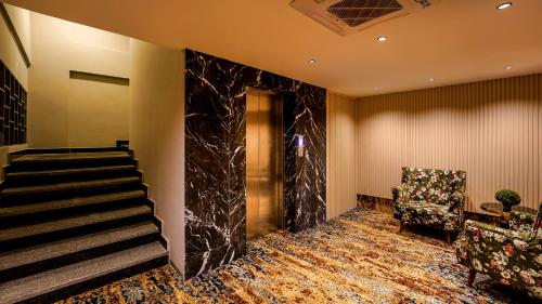 a lobby with a staircase and a chair at City Keys Bangalore By Bestinn Leisure in Bengaluru