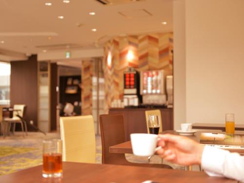 a person sitting at a table with a glass of wine at Hotel New Gaea Domemae in Fukuoka